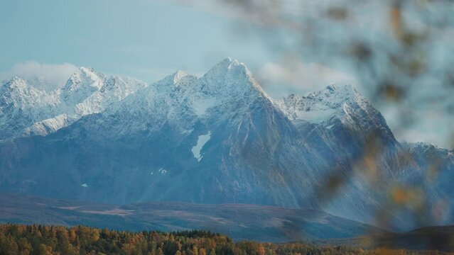 Snow-capped mountains fower above the autumn valley.