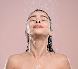 Woman, relax and shower with water drops for hygiene, stress relief or wash on a pink studio background. Calm female person or young model with natural liquid for skincare, hydration or cleanliness