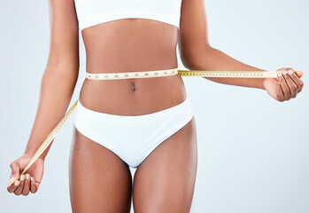 Woman, stomach and body with tape measure in studio on white background with underwear, progress...