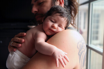 Dark Haired Father Holding Baby Over Shoulder