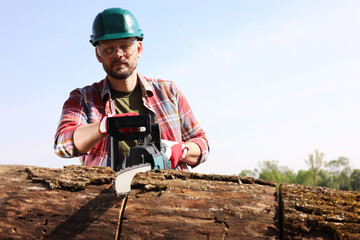 Man sawing wooden log on sunny day