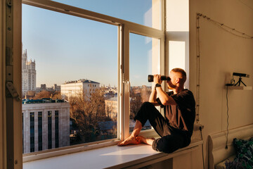 Man surveying urban landscape with Binoculars from apartment