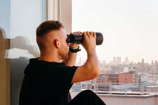 A man surveying the urban landscape with Binoculars