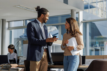 Smiling multiracial colleagues discussing in office