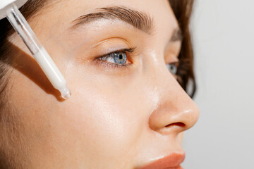 A young woman applying a face and body oil 