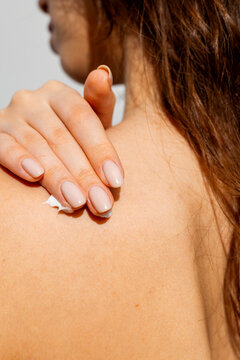 A woman puts body cream on her back