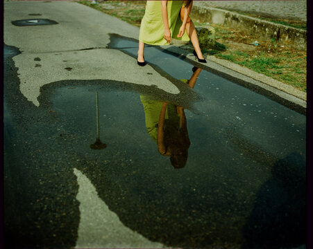 Woman Leaning Over Water Puddle