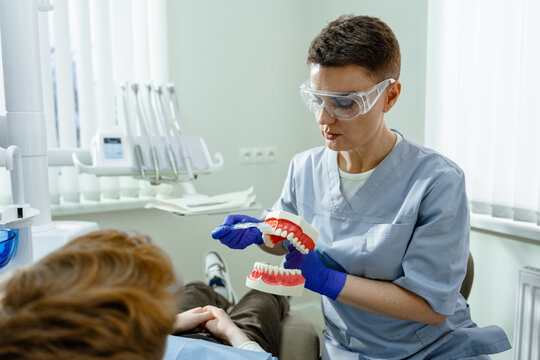A dentist shows a patient how to brush his teeth