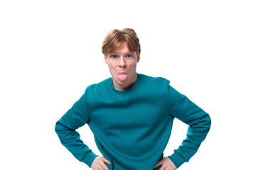 young handsome red-haired man with a blue sweater looks attentively at the camera