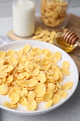Breakfast cereal. Corn flakes and milk in bowl on light grey table, closeup