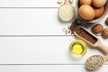 Different products high in natural fats on white wooden table, flat lay. Space for text