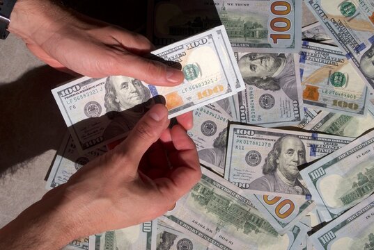 Counting a pile of hundred dollar bills closeup