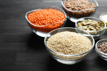 Different seeds high in healthy fats on black wooden table, closeup. Space for text