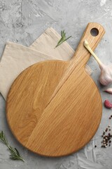 Cutting board, garlic, spices and rosemary on grey textured table, flat lay. Space for text