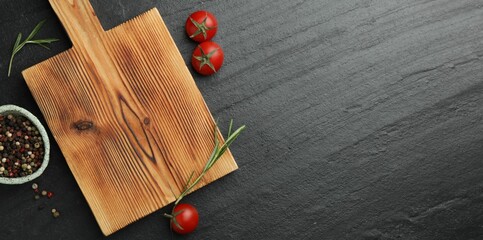 Wooden cutting board, fresh tomatoes and different spices on grey textured table, flat lay. Space...