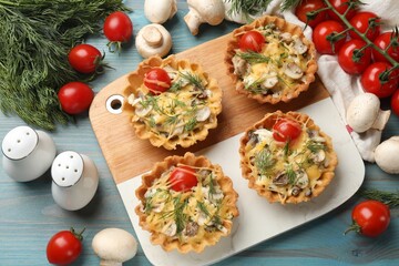 Tasty tartlets with cheese, tomatoes, mushrooms and dill on turquoise wooden table, flat lay