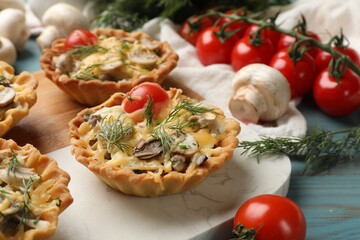 Tasty tartlets with cheese, tomatoes, mushrooms and dill on table, closeup