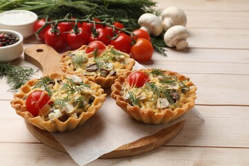Tasty tartlets with cheese, tomatoes, mushrooms and dill on wooden table, closeup