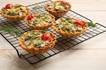 Tasty tartlets with cheese, tomatoes, mushrooms and dill on wooden table, closeup