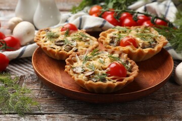 Tasty tartlets with cheese, tomatoes, mushrooms and dill on wooden rustic table, closeup