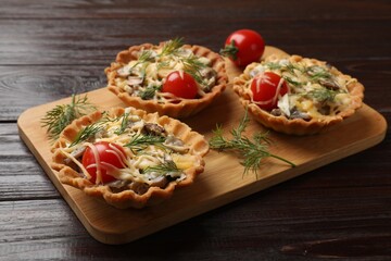 Tasty tartlets with cheese, tomatoes, mushrooms and dill on wooden table, closeup