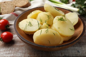 Young boiled potatoes with dill in bowl on wooden rustic table, closeup