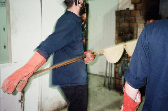 Jewish Baker Slides Matzah Onto Baking Pole For Oven Insertion.