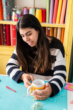 Craftswoman measuring ribbon in colorful workshop