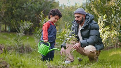 A caring father teaches his young child to plant a sapling, sharing a moment of learning and bonding in the garden. - Powered by Adobe