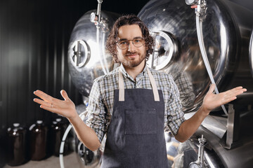 Concept owner small business craft brewery. Portrait brewer happy bearded man in apron on background beer tank