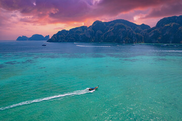 Vibrant aerial shot of traditional thai long tail boat speeding near lush tropical island coast,...