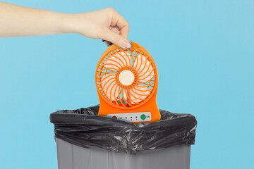 throw the portable table fan into the trash, outstretched hand with fan in front of the trash can