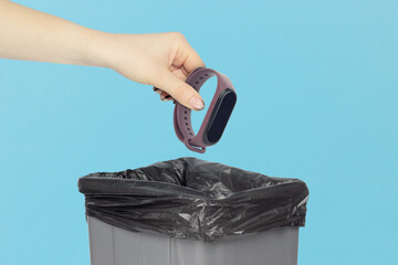throw the smart watch into the trash, outstretched hand with smart watch in front of the trash can