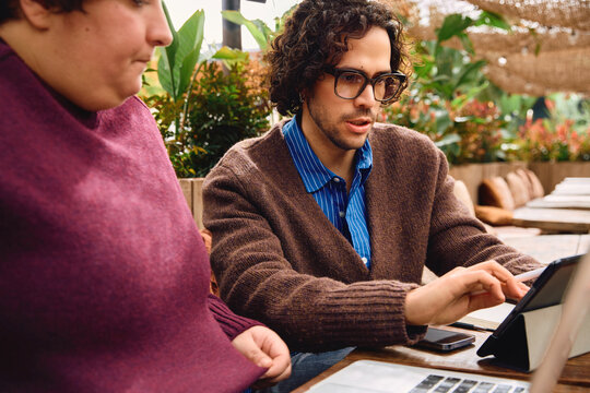 Young man and woman working remotely at a cafe.