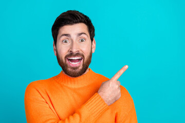 Photo of cheerful glad nice man wear orange trendy clothes demonstrate empty space isolated on cyan...
