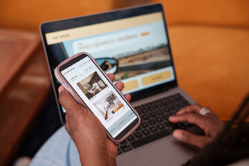 Anonymous planning vacation trip with laptop and smartphone