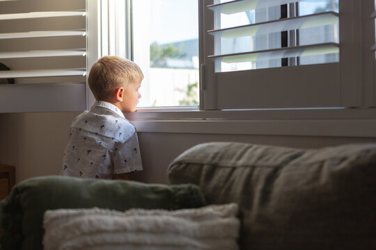 Young boy looking longingly out a window