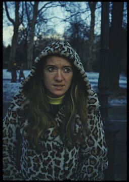 70's film photo. Woman by a snowy park in cold weather wearing coat 