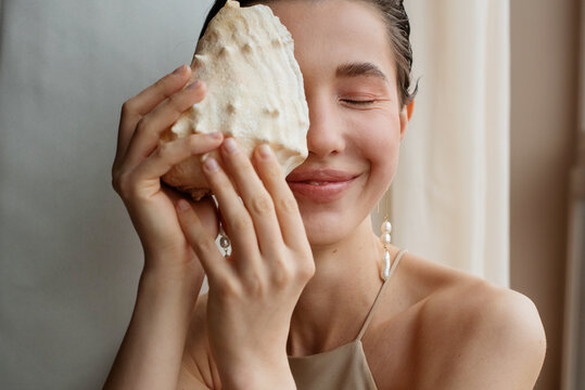 Happy woman closes her eye with a seashell