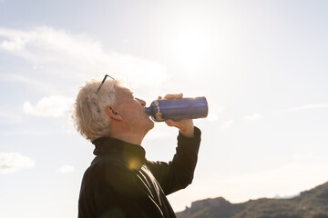 Senior hiker drinking water in the mountain