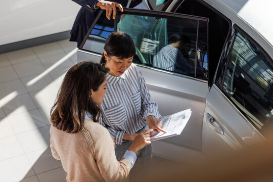 Customer and car salesperson pointing at details of the contract