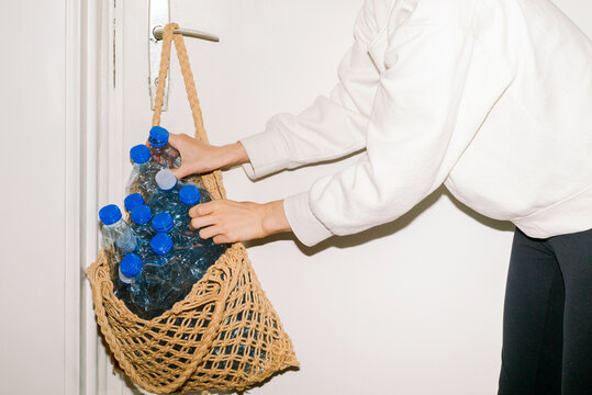 A young woman puts compressed plastic bottles into a bag