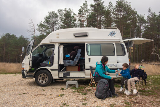 Woman camping by the van with her kids