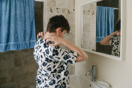 tween boy getting dressed in the morning fixing his collar 