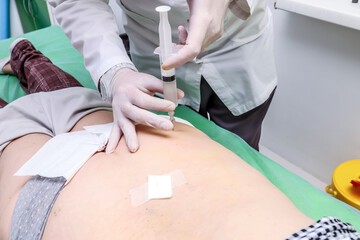 An injection in the lumbar region for problems with the spine and pinching of the sciatic nerve