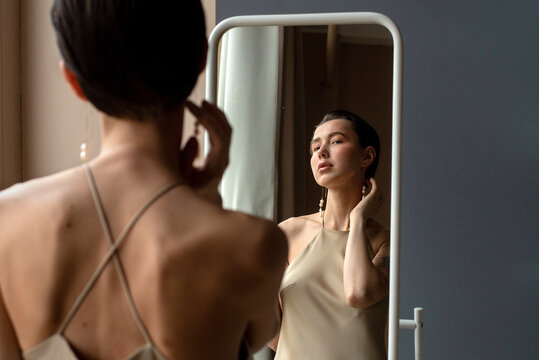 Elegant Woman Adjusting Her Earring in Front of a Mirror