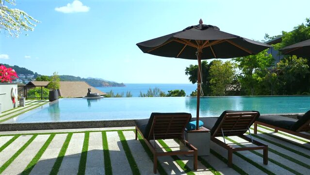 Luxurious tropical resort infinity pool overlooking ocean, with lounge chairs and umbrella providing relaxation and leisure by water. Resort travel and luxury vacation.