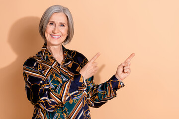 Photo of pleasant clever person with gray hairdo wear print blouse indicating at sale empty space isolated on beige color background