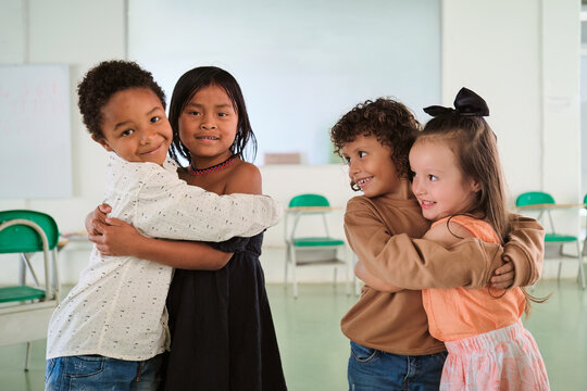 Primary school classmates hugging in the classroom