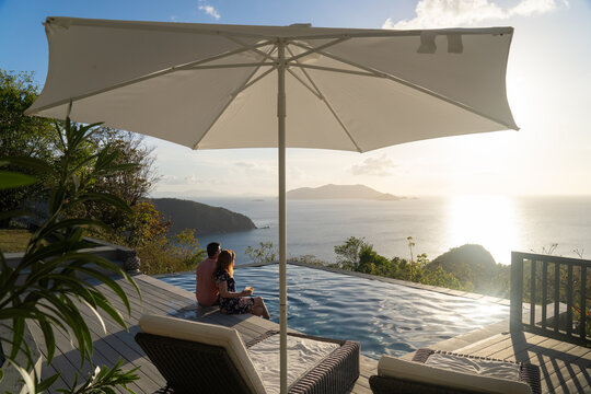 Couple Sitting by Pool With Cocktails and Ocean View at Caribbea